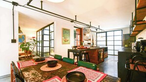 A modern kitchen with a central island, green chairs, and a dining table set with placemats and bowls. - w Bright Colonial 5BR House With Balcony (Medellín)