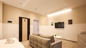 Une chambre d’hôtel avec un lit, un canapé, une petite table, une télévision et une salle de bain.