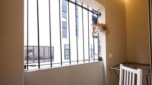 Une pièce avec une fenêtre, un étendoir et une chaise blanche.