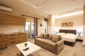 A modern hotel room with a kitchenette, a sofa, a bed, and a bedside table. - Azzurra Studio 04 in Durr s (Durrës)