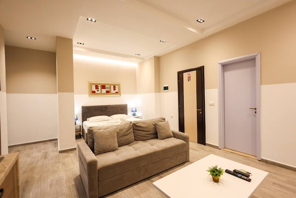 A modern hotel room with a sofa, a bed, a nightstand, and a door. - Azzurra Studio 04 in Durr s (Durrës)