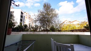 A balcony with a drying rack, a white chair, and a view of buildings and trees. - Azzurra Studio 02 in Durr s (Durrës)