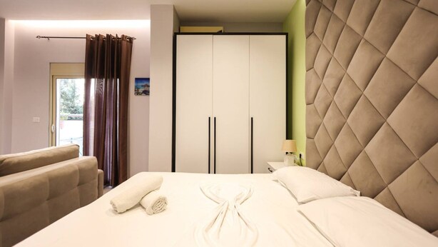 A hotel room with a bed, a sofa, a wardrobe, and a window with curtains. - Azzurra Studio 02 in Durr s (Durrës)