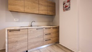 A kitchen with wooden cabinets, a sink, and a countertop. - Azzurra Studio 02 in Durr s (Durrës)