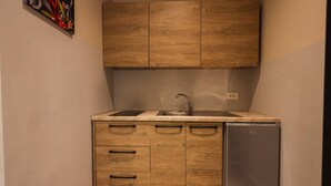 A compact kitchen with wooden cabinets, a sink, and a built-in refrigerator. - Azzurra Studio 01 in Durr s (Durrës)