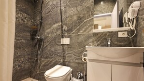 A bathroom with a marble wall, a toilet, a sink, and a shower. - Azzurra Studio 01 in Durr s (Durrës)