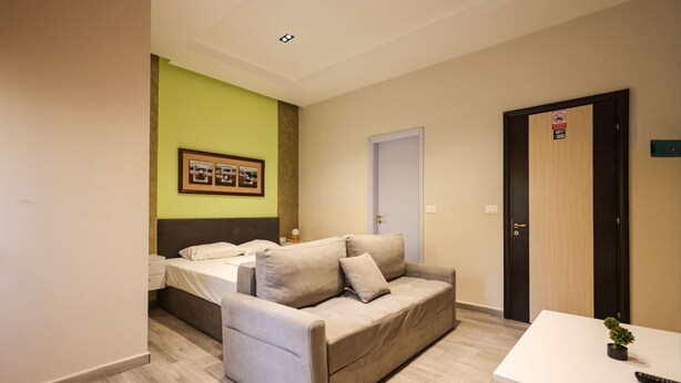 A room with a bed, a sofa, a small table, and a door with a sign. - Azzurra Studio 01 in Durr s (Durrës)