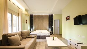 A modern hotel room with a bed, a sofa, a TV, and a small table. - Azzurra Studio 03 in Durr s (Durrës)