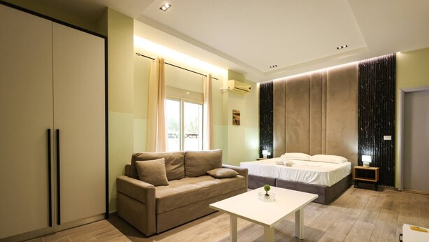 A modern bedroom with a bed, a sofa, a bedside table, and a wardrobe. - Azzurra Studio 03 in Durr s (Durrës)