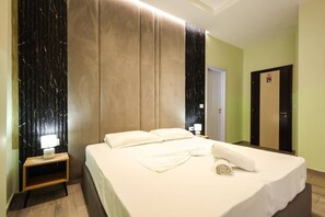 A hotel room with a large bed, a nightstand with a lamp, and a door with a sign. - Azzurra Studio 03 in Durr s (Durrës)