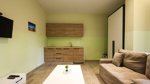 A modern living room with a white coffee table, a beige sofa, and a wooden cabinet with a sink. - Azzurra Studio 03 in Durr s (Durrës)