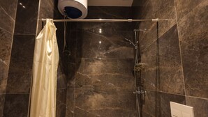 Ein Duschbereich mit Glastür, Handtuchhalter und einer Bedienfeld an der Wand.