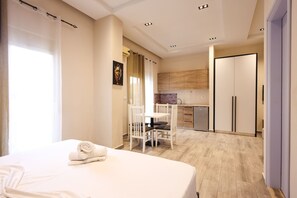 A hotel room with a bed, a small table, and chairs. There is a kitchenette with cabinets and a refrigerator. - Azzurra Studio 05 in Durr s (Durrës)