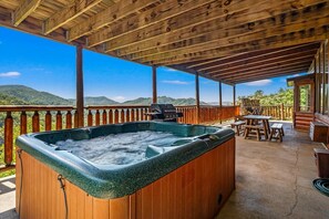 A wooden deck with a hot tub, outdoor seating, and a scenic mountain view. - 3BR Resort Cabin w/Views! Hot Tub*Games*Comm Pool (Sevierville)
