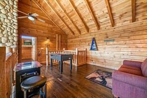 A cozy wooden interior with a foosball table, a sofa, and a ceiling fan. - 3BR Resort Cabin w/Views! Hot Tub*Games*Comm Pool (Sevierville)