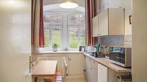 A compact kitchen with a window, a radiator, a table, and a refrigerator. - Apartment at the Saxon Switzerland National Park (Sebnitz)