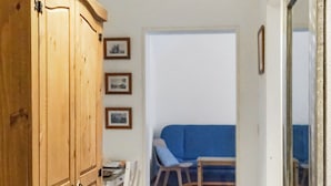 A hallway with a wooden wardrobe, a dining table with chairs, a blue sofa, and a framed picture on the wall. - Apartment at the Saxon Switzerland National Park (Sebnitz)