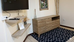 Una sala moderna con televisor de pantalla plana, consola de madera y alfombra estampada.