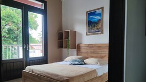 Un dormitorio con cama de madera, una ventana con vistas a la vegetación y un cartel en la pared.