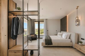 Ein modernes Schlafzimmer mit einem großen Bett, einem Kleiderschrank und einer Sitzecke mit Blick.