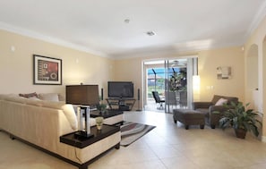 A living room with a sofa, a coffee table, a TV, and a dining area with chairs and a table. - Experience the Florida dream at Villa Barbara in Cape Coral! (Cape Coral)