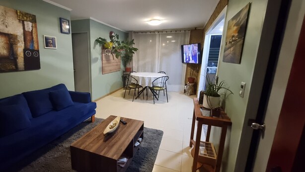Ein Wohnzimmer mit einem blauen Sofa, einem Holztisch und einem Essbereich mit Tisch und Stühlen.