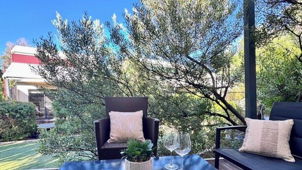 Un espacio al aire libre con mesa, dos sillas y una planta pequeña.