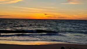 Una playa con olas y un atardecer.