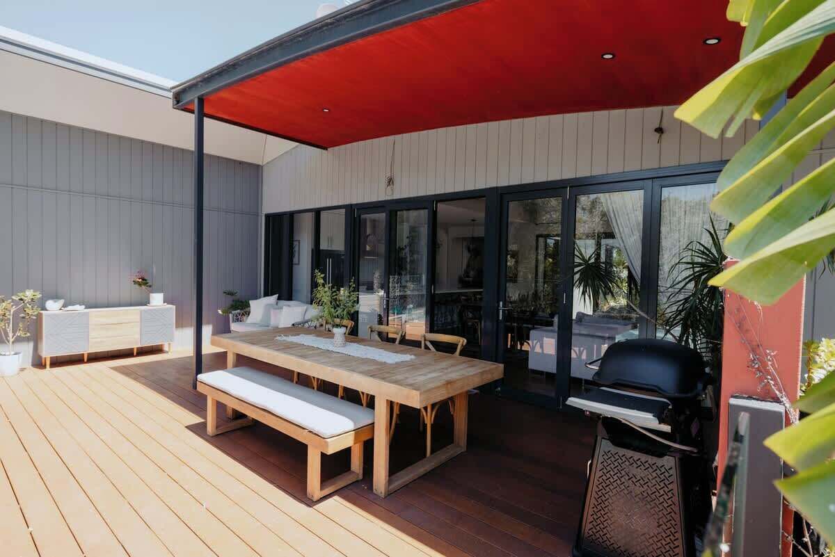 Eine Terrassengruppe im Freien mit Holztisch und -bänken, einem Grill und einem überdachten Sitzbereich.
