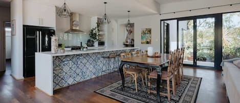 Una cucina moderna con isola centrale, elettrodomestici neri e lampade a sospensione.