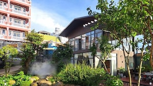 A hotel with a garden featuring a small waterfall, potted plants, and a variety of flowers. - Khu Vuon Cua Nang Le Jardin De Nang (Cam Ly - Da Lat)