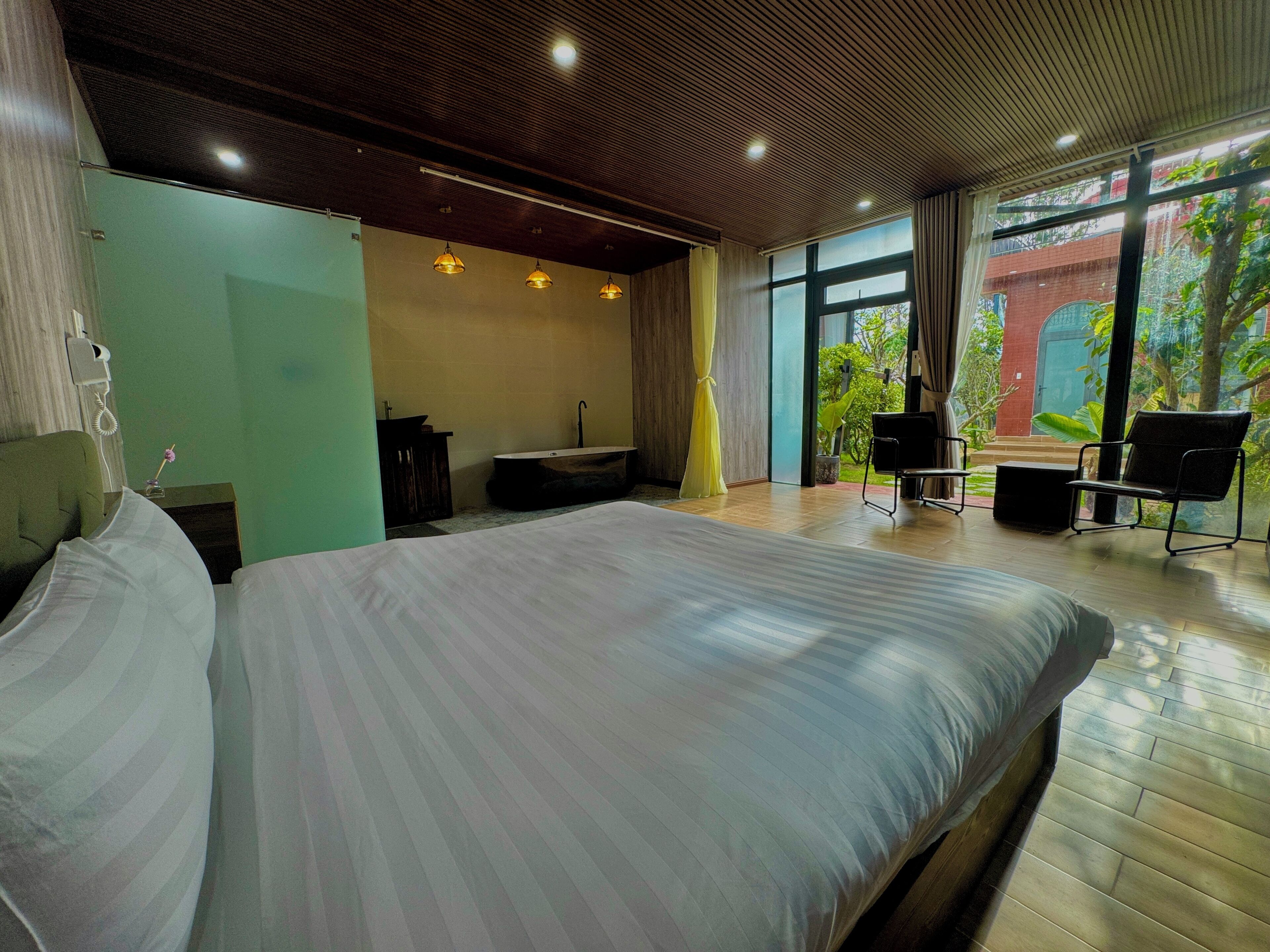 A modern hotel room with a large bed, a desk, a chair, and a view of the outdoors.