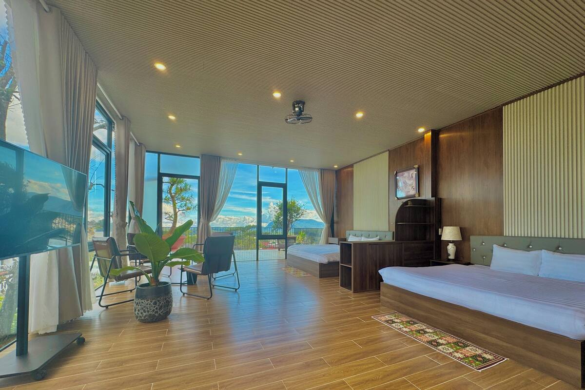 Habitación de hotel amplia con una cama grande, un escritorio y un televisor. Cuenta con un balcón con vistas a la ciudad.