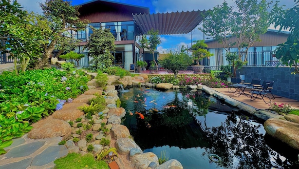 A modern hotel with a koi pond, outdoor seating, and lush landscaping. - Khu Vuon Cua Nang Le Jardin De Nang (Cam Ly - Da Lat)
