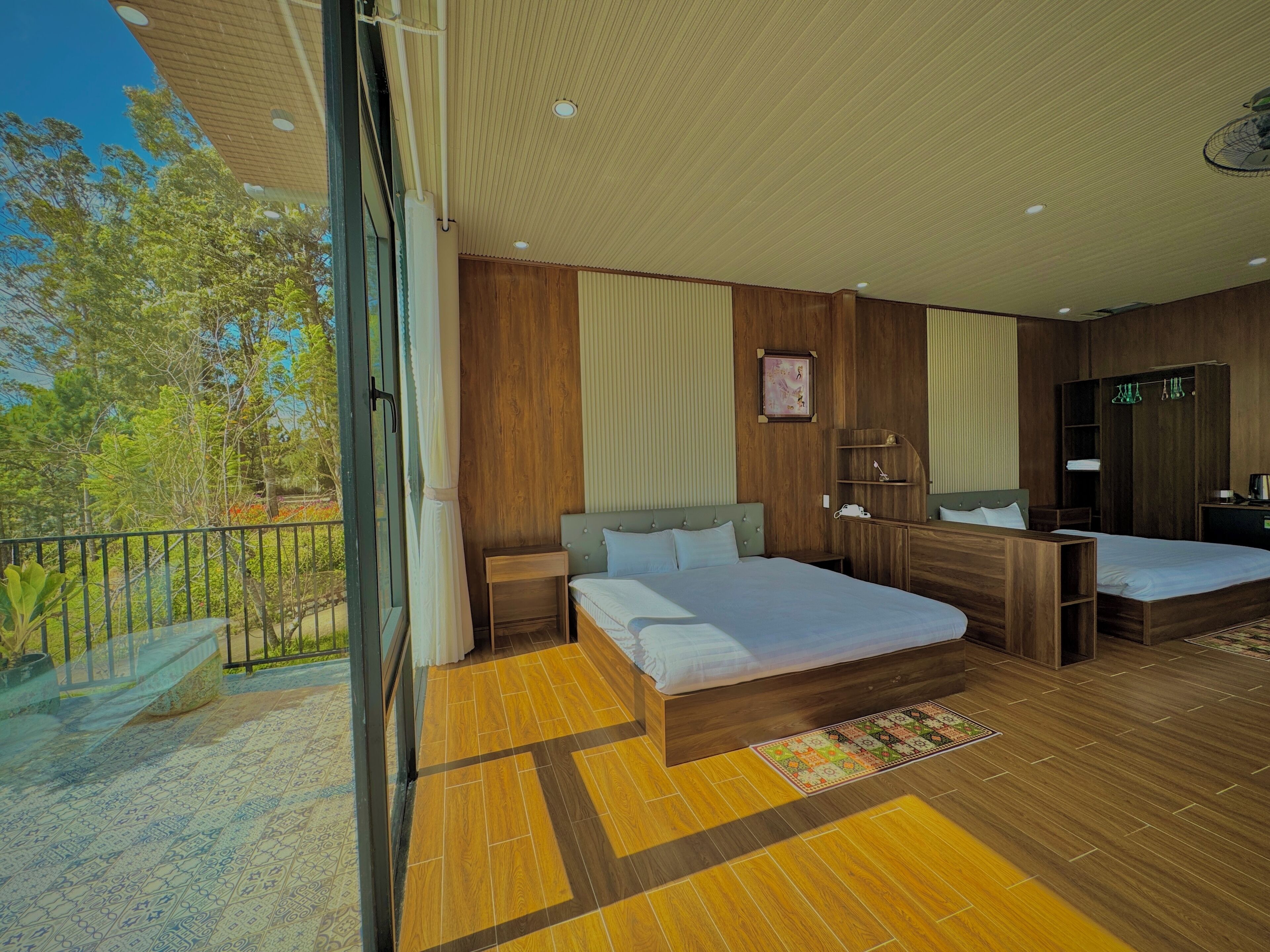 A modern bedroom with two beds, a wooden floor, a balcony, and a large window.
