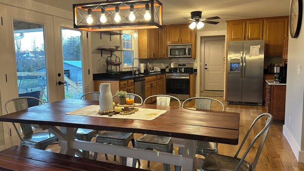 Cocina con armarios de madera, refrigerador de acero inoxidable, microondas y ventilador de techo.