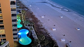Luftaufnahme eines Hotels mit Poolbereich, Zugang zum Strand und einem Gebäude mit Balkonen.