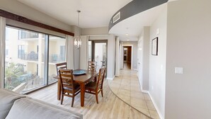 A dining area with a wooden table and chairs, large windows, and a view of a balcony. - Chic Condo w/ Poolside Balcony & Gulf Views. Free Golf & Daily Activities! (Panama City Beach)