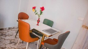 A dining area with a table, four chairs, and a vase with flowers.