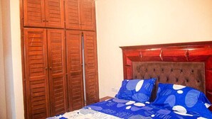 A bedroom with a bed, blue patterned bedding, and a wooden wardrobe.