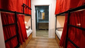 A narrow hallway with bunk beds on either side, leading to a bathroom with a sink and mirror. - Fit Hostel Madrid (Madrid)