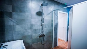 A modern bathroom with a shower, a sink, and a door leading to another room. - Fit Hostel Madrid (Madrid)