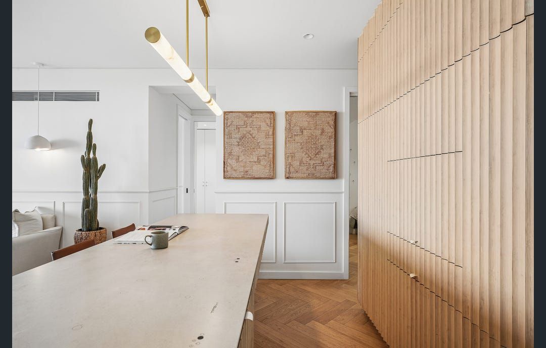 A modern kitchen with a wooden island, pendant lighting, and a cactus plant.