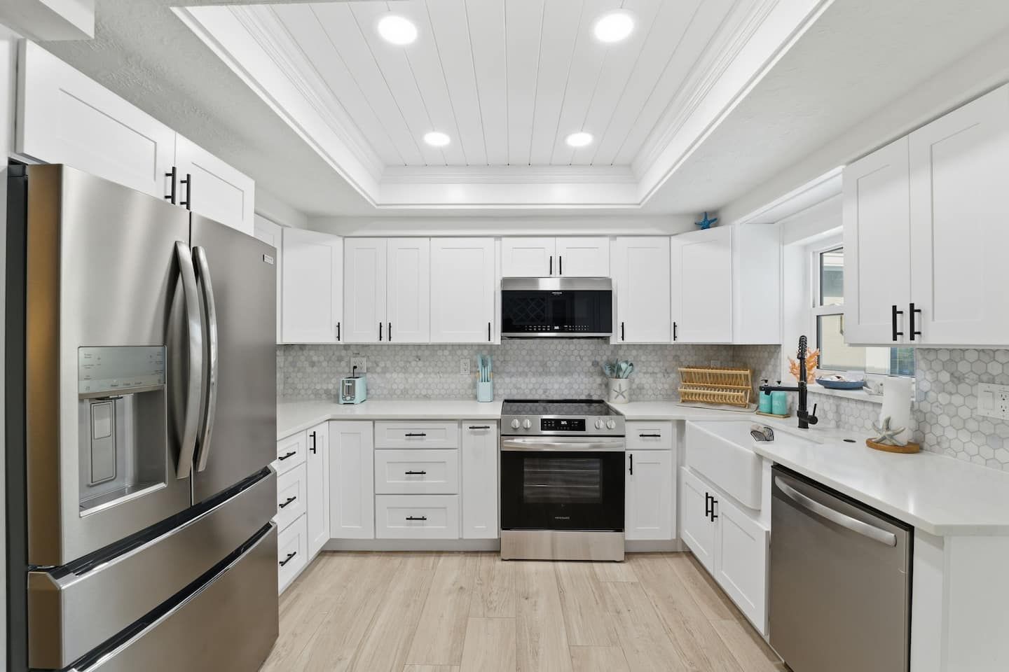 A modern kitchen with white cabinetry, stainless steel appliances, and a central island.
