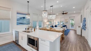 A modern kitchen with a large island, stainless steel appliances, and pendant lighting.