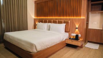 A hotel room with a large bed, wooden headboard, bedside tables, and a nightstand with a coffee maker.