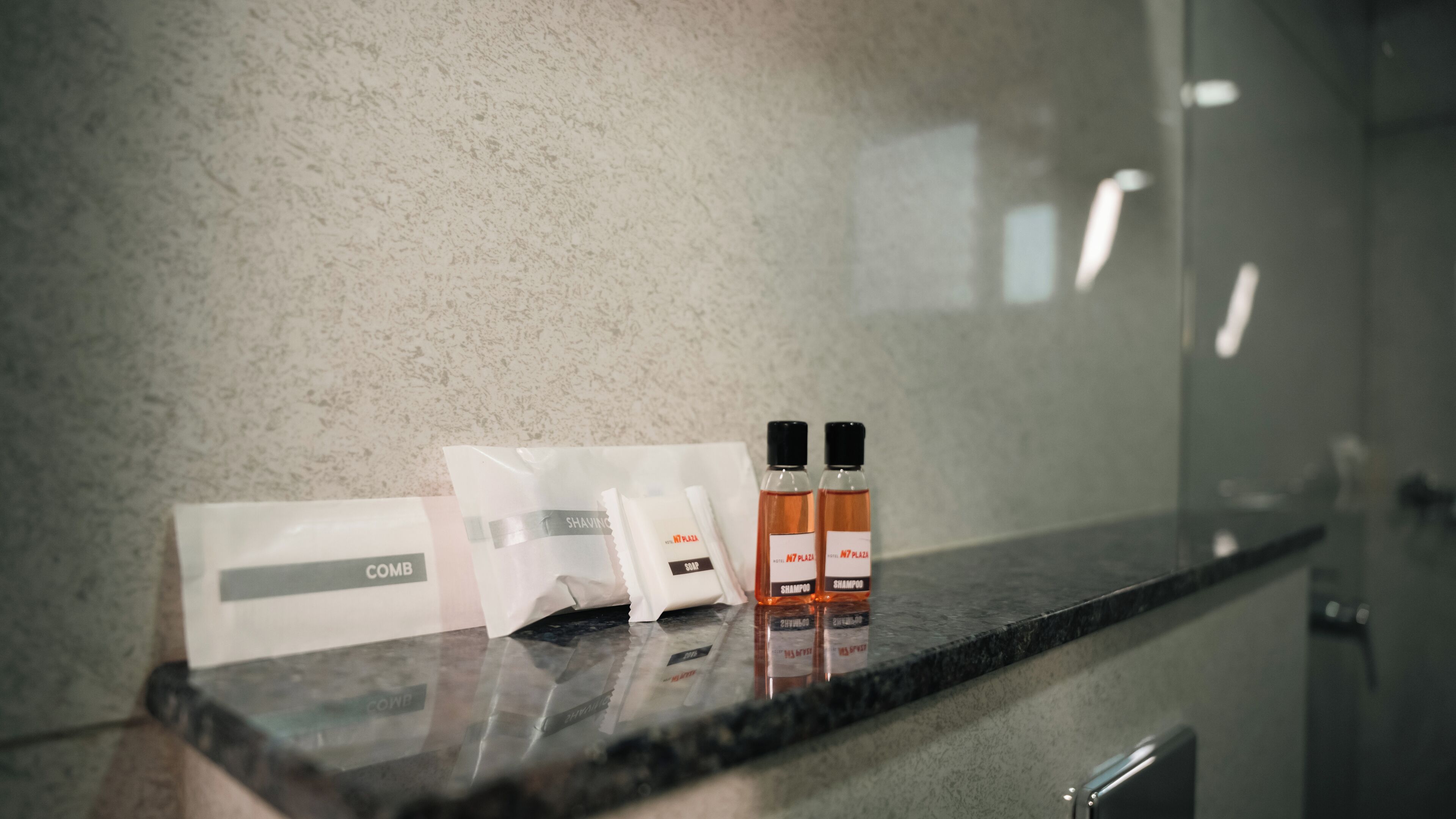 A bathroom counter with toiletries including combs, shampoo, and conditioner.