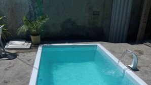 Een rechthoekig zwembad met helder water, omringd door een betonnen terras.