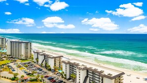 A coastal hotel with multiple buildings, a parking lot, and a beach view. - Penthouse Premium 3BR Condo - 1900+ Sq Ft - Beach Service Included (Panama City Beach)