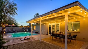 A covered outdoor patio with a pool, lounge chairs, and a dining area. - Stylish Phoenix home | Private pool | Spacious living | Family & sports-friendly | Close to Phoenix Zoo, Desert Botanical Garden, ASU, and State Farm Stadium (Phoenix)